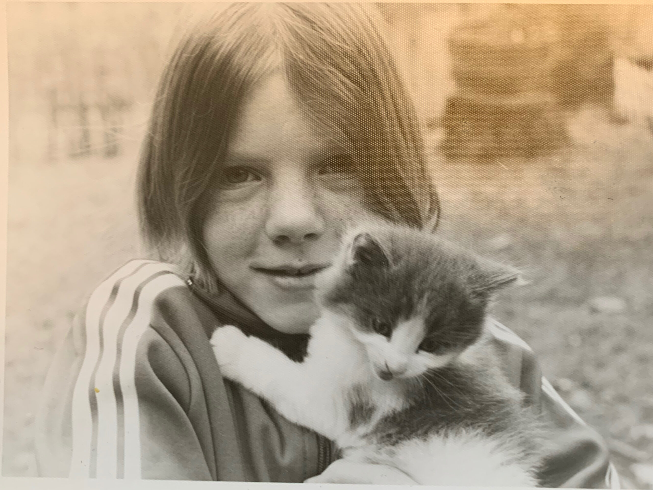 black and white photo with young freckled girl holding a kitten
