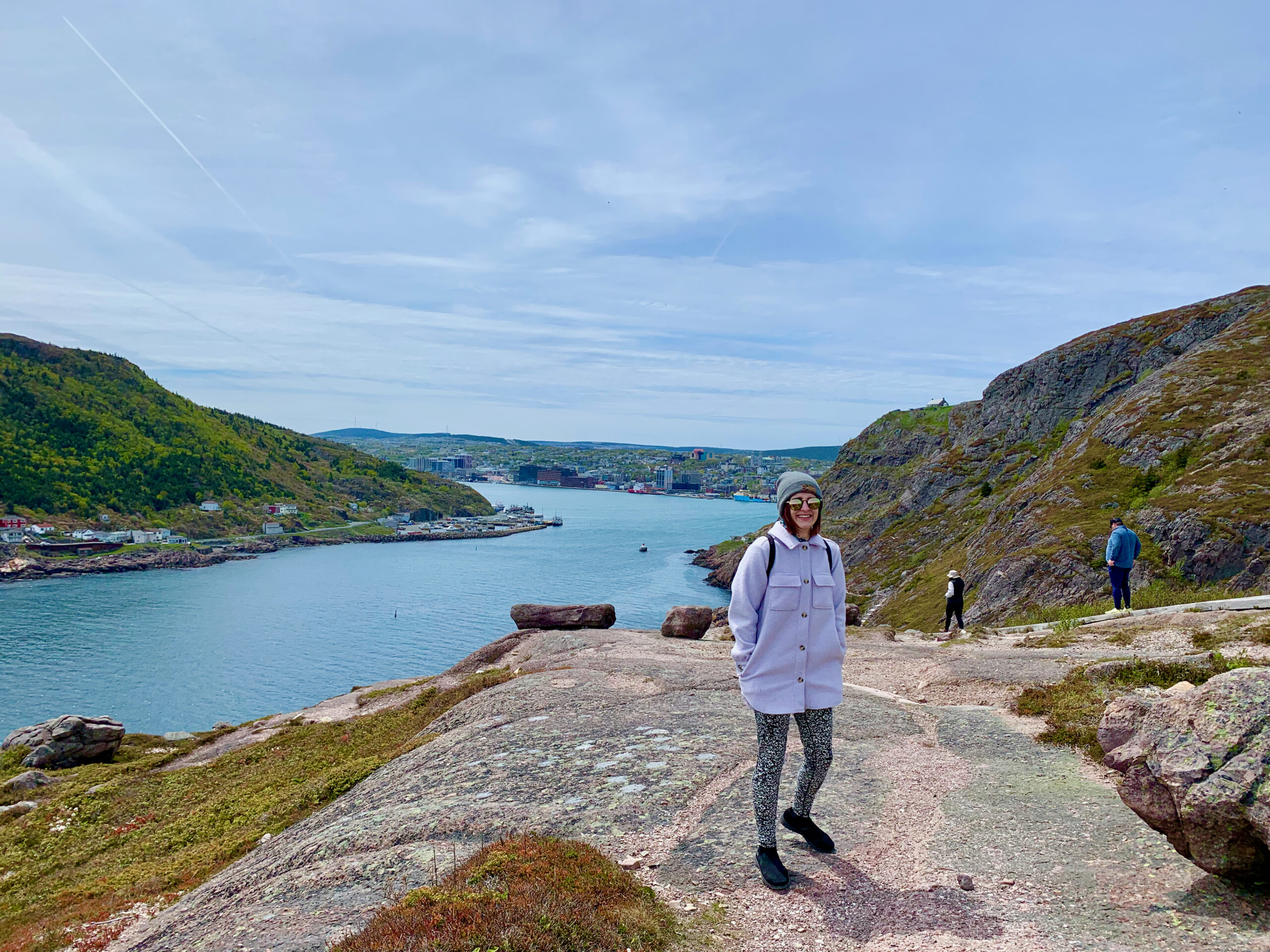 Young woman on a rocky hill with the St. John's Harbour behind her.