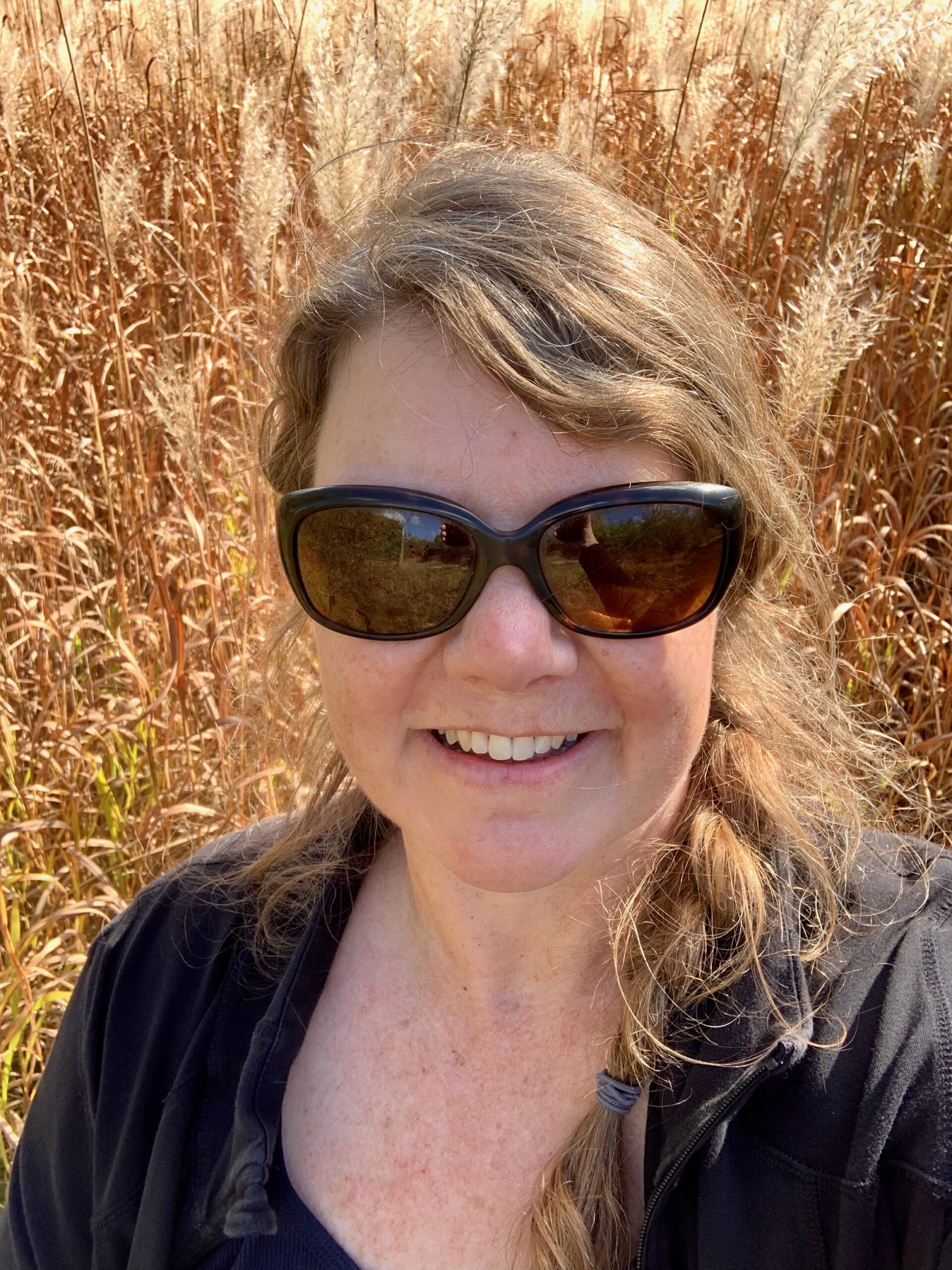 me wearing sunglasses in front of a field of tall fall grass