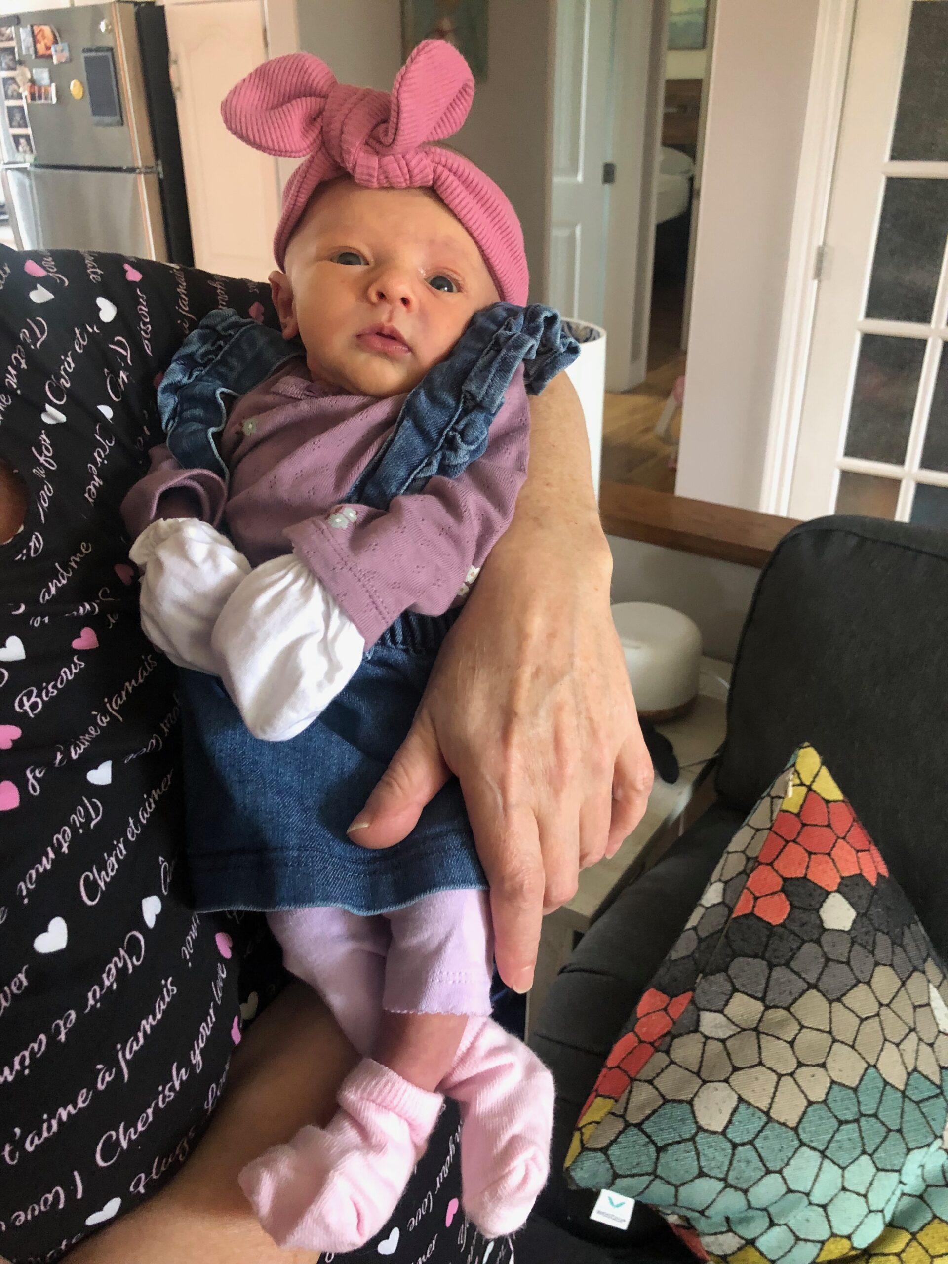 newborn baby being held; she's wearing a big pink head tie