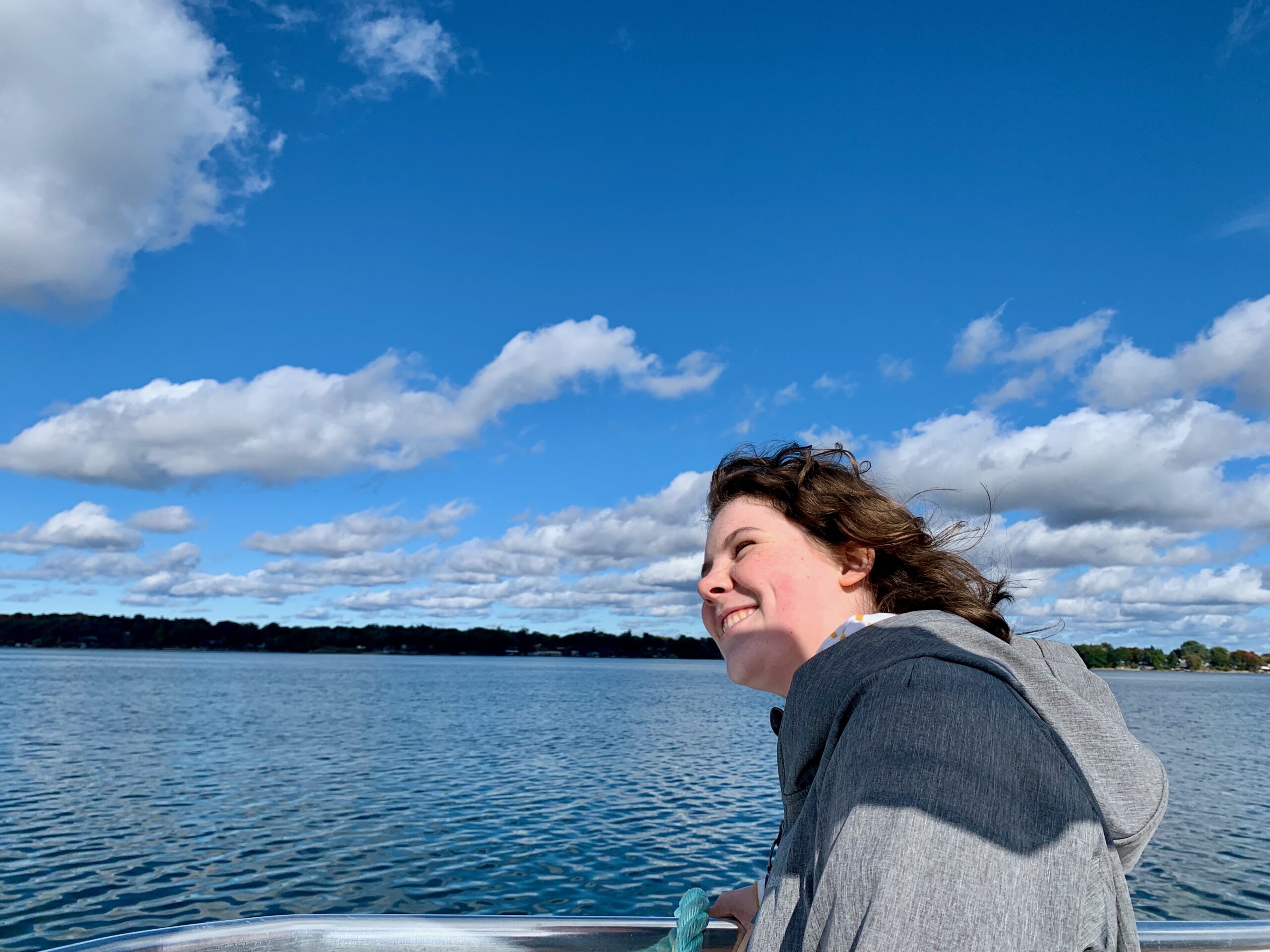 Young woman smiling as she looks over the front of a boat.