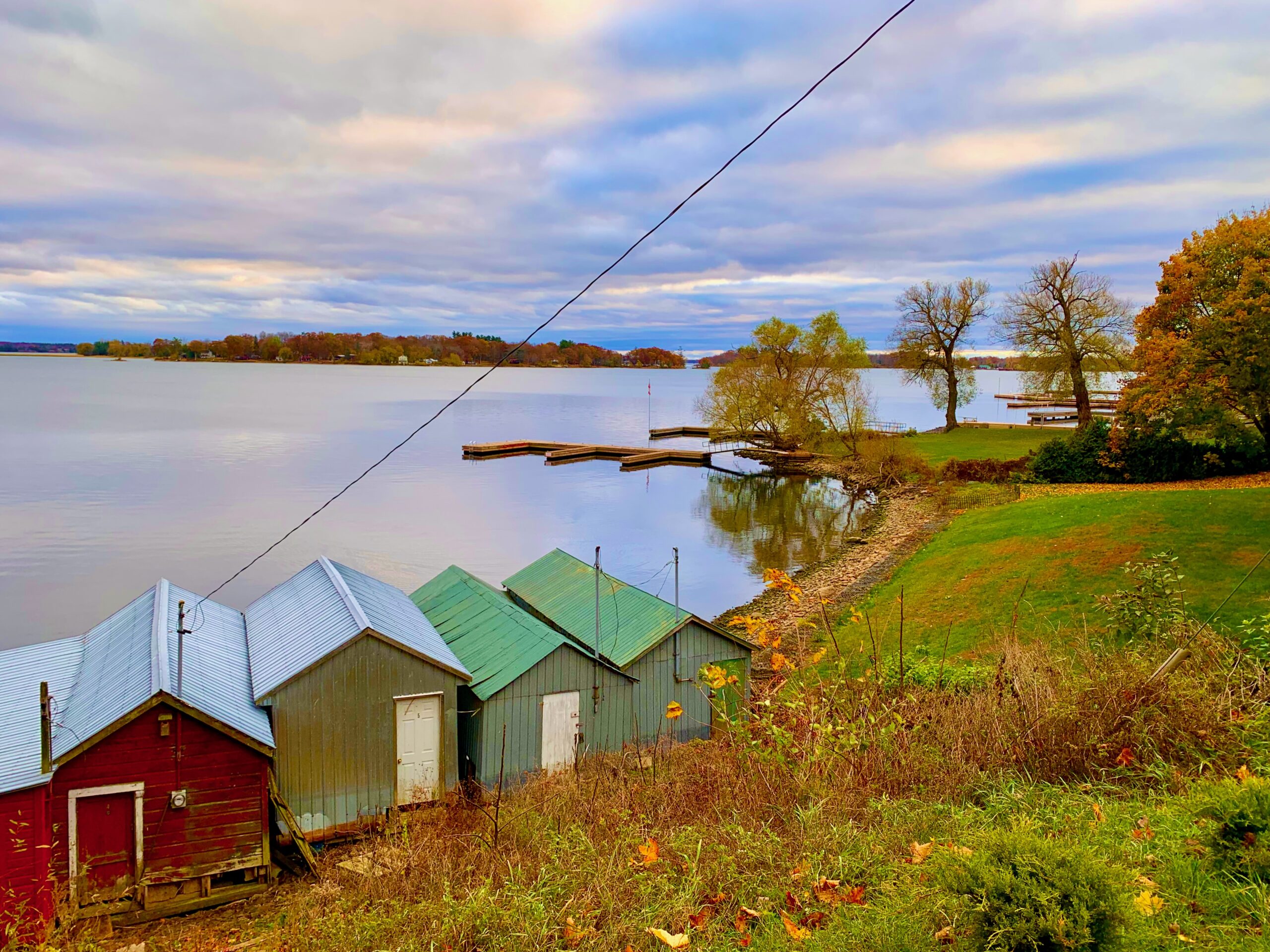 Colourful boat houses along a still river with fall colours reflecting.
